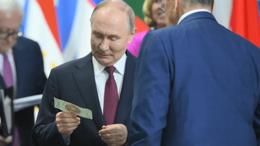 Vladímir Putin durante la reunión de Los BRICS sosteniendo el billete donde se muestra la bandera de México